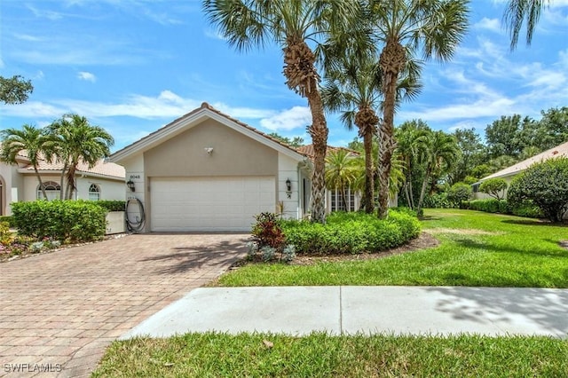 view of front facade with a front yard, stucco siding, decorative driveway, and an attached garage