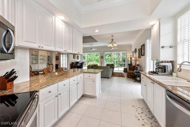 kitchen with white cabinetry, ornamental molding, a peninsula, and appliances with stainless steel finishes