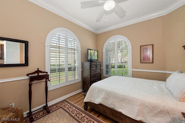 bedroom featuring ornamental molding, multiple windows, wood finished floors, and baseboards