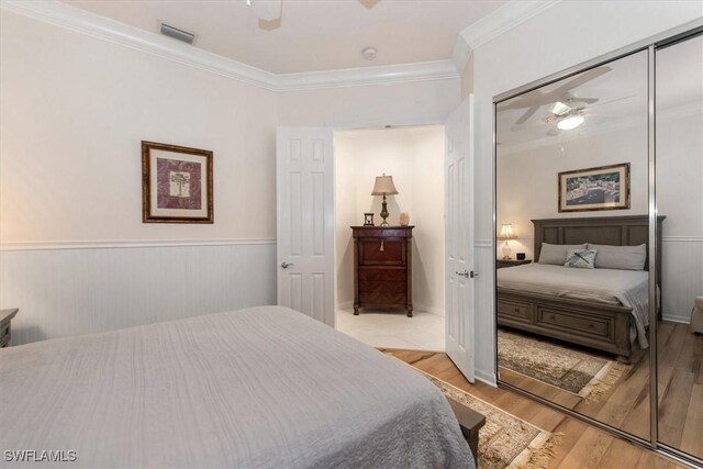 bedroom featuring visible vents, ornamental molding, light wood-type flooring, and a ceiling fan