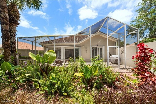back of property featuring stucco siding, a patio, and glass enclosure