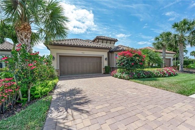 mediterranean / spanish-style home featuring stucco siding, a tile roof, decorative driveway, and a garage