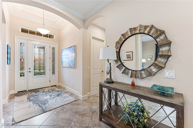 foyer featuring arched walkways, baseboards, and ornamental molding