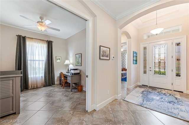 entryway featuring arched walkways, crown molding, baseboards, and ceiling fan