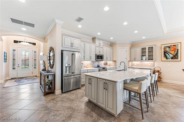 kitchen with a breakfast bar, visible vents, ornamental molding, a sink, and high quality appliances