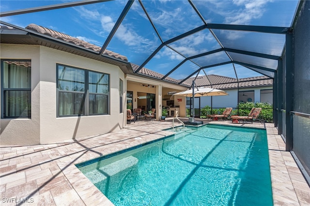 pool with a patio area, glass enclosure, and ceiling fan