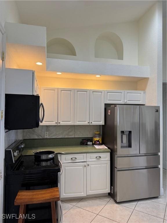 4328 NW 27th Ter, Cape Coral, FL 33993 - kitchen with stainless steel refrigerator with ice dispenser, electric range, black microwave, light tile patterned floors, and white cabinets