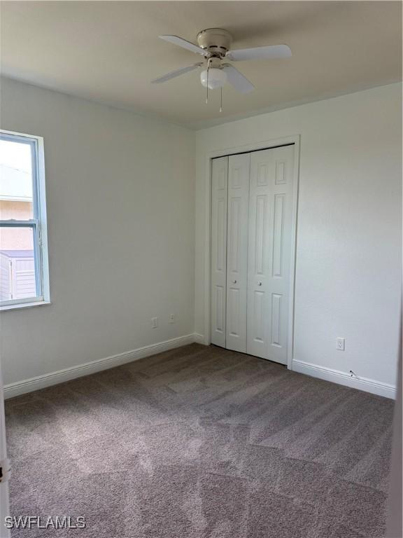 4328 NW 27th Ter, Cape Coral, FL 33993 - unfurnished bedroom with dark carpet, baseboards, a closet, and ceiling fan