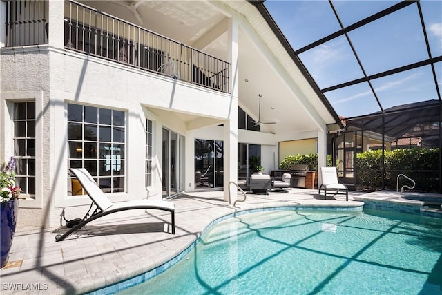 view of swimming pool with a ceiling fan, a patio, glass enclosure, and a pool with connected hot tub
