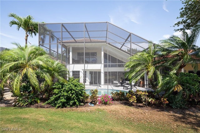 back of property with an outdoor pool, a yard, a patio, and glass enclosure