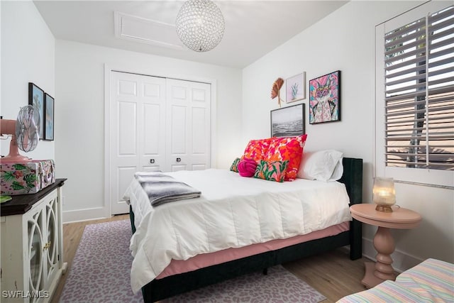 bedroom with baseboards, wood finished floors, multiple windows, and a closet