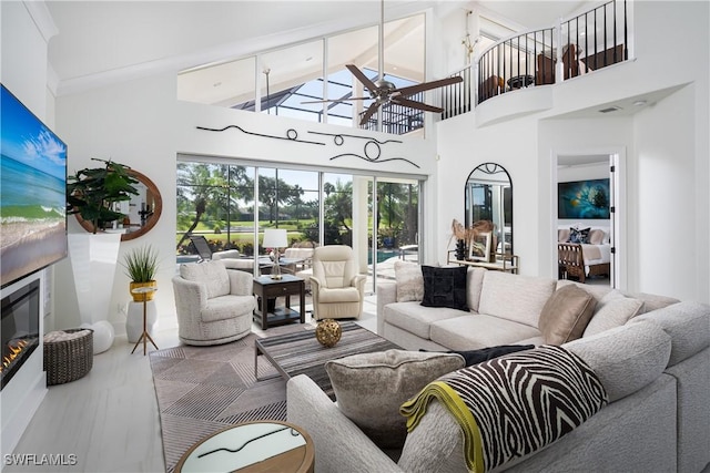 living area with visible vents, a glass covered fireplace, ceiling fan, and high vaulted ceiling