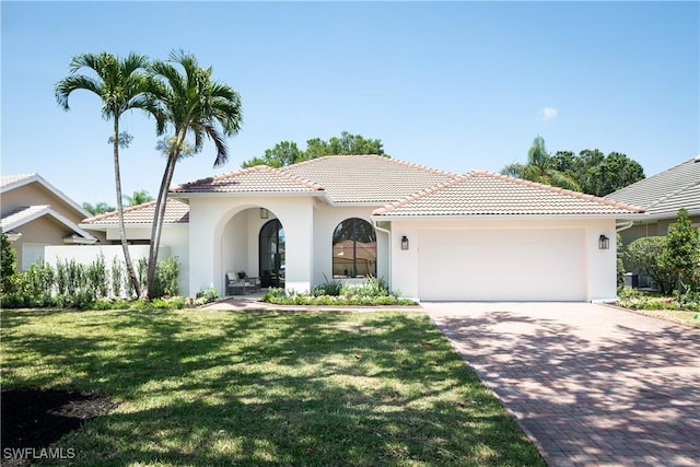 204 Monterey Dr, Naples, FL 34119 - mediterranean / spanish home featuring an attached garage, decorative driveway, stucco siding, a front yard, and a tiled roof