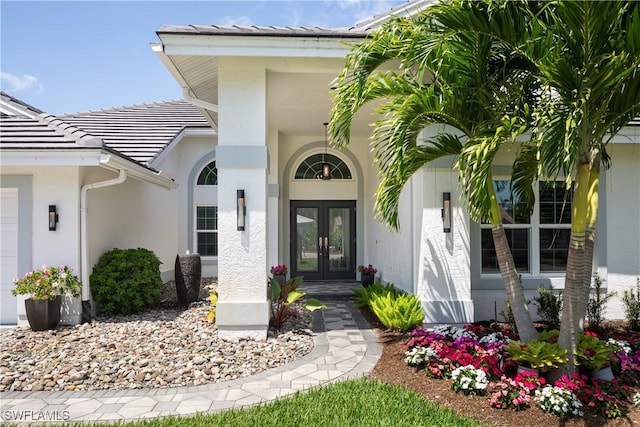 view of exterior entry featuring stucco siding, a tiled roof, and french doors