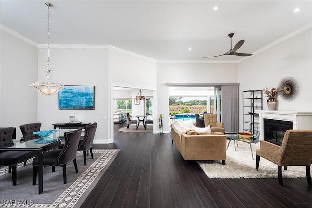 living area with dark wood finished floors, ceiling fan, crown molding, and a glass covered fireplace
