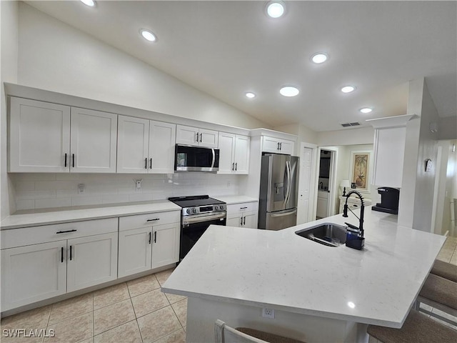 19942 Lake Vista Cir N Unit 2, Lehigh Acres, FL 33936 - kitchen with a peninsula, a sink, lofted ceiling, decorative backsplash, and appliances with stainless steel finishes