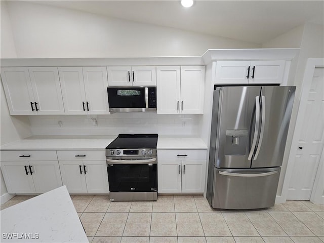 19942 Lake Vista Cir N Unit 2, Lehigh Acres, FL 33936 - kitchen with light countertops, vaulted ceiling, white cabinets, and stainless steel appliances