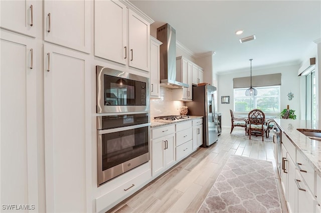 15951 Talon Ter, Punta Gorda, FL 33982 - kitchen featuring white cabinetry, appliances with stainless steel finishes, ornamental molding, and wall chimney exhaust hood
