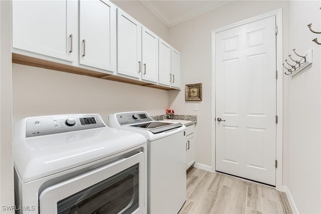 15951 Talon Ter, Punta Gorda, FL 33982 - laundry area with washing machine and clothes dryer, cabinet space, a sink, ornamental molding, and light wood-style flooring