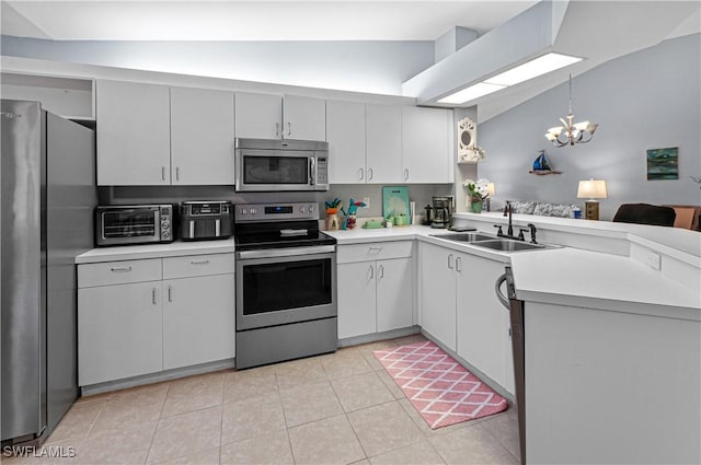 kitchen with stainless steel appliances, a toaster, a sink, an inviting chandelier, and light countertops