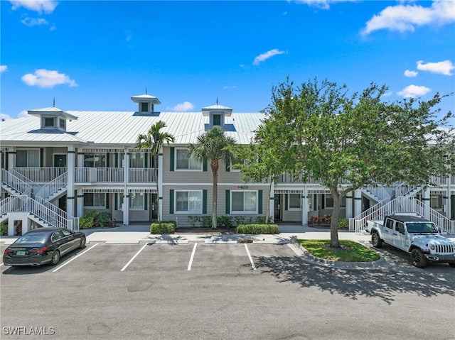view of building exterior with stairway and uncovered parking