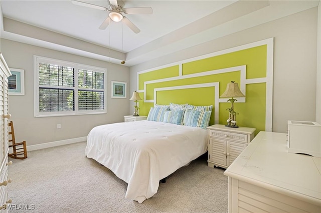 carpeted bedroom featuring baseboards, a ceiling fan, and a raised ceiling