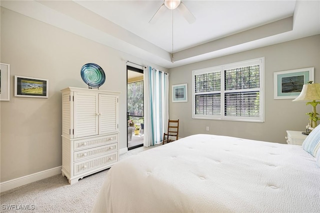 bedroom with access to outside, carpet flooring, baseboards, ceiling fan, and a tray ceiling