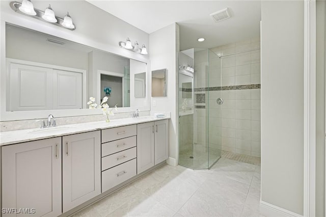 bathroom featuring a tile shower, double vanity, and baseboards