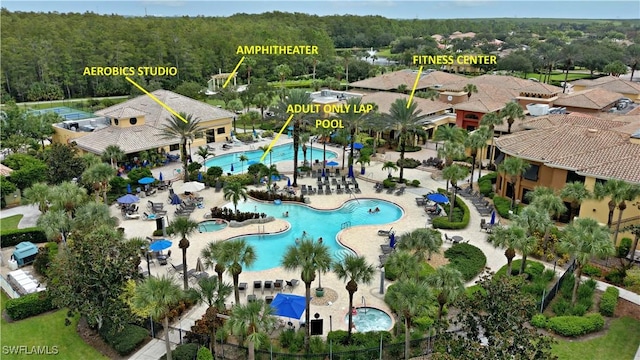 drone / aerial view of a pool area and a heavily wooded area