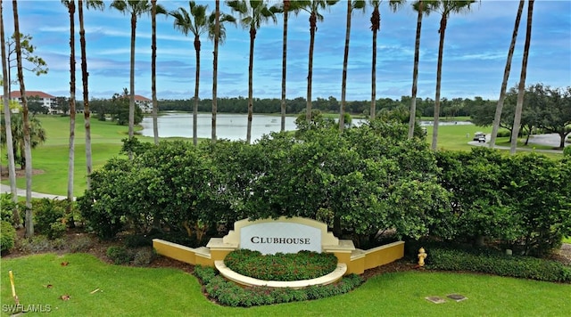community / neighborhood sign featuring a water view, a lawn, and golf course view