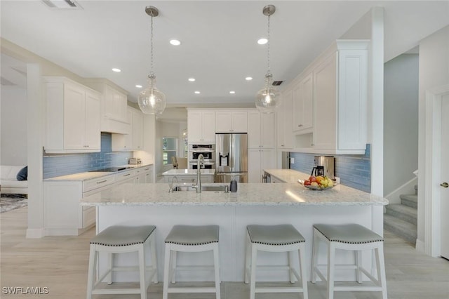 25011 Goldcrest Dr, Bonita Springs, FL 34134 - kitchen featuring a sink, stainless steel fridge with ice dispenser, black electric stovetop, backsplash, and a peninsula