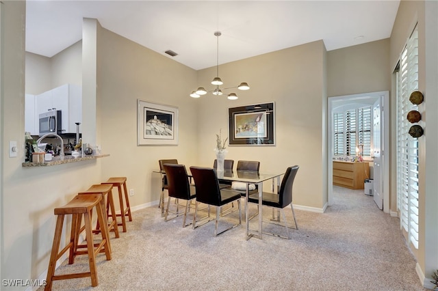 dining space with baseboards, a wealth of natural light, an inviting chandelier, and light colored carpet