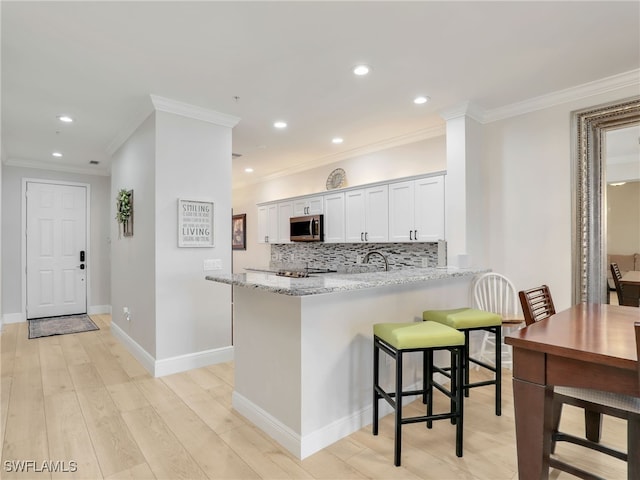 28436 Altessa Way Unit 102, Bonita Springs, FL 34135 - kitchen with crown molding, light stone countertops, light wood finished floors, stainless steel microwave, and decorative backsplash