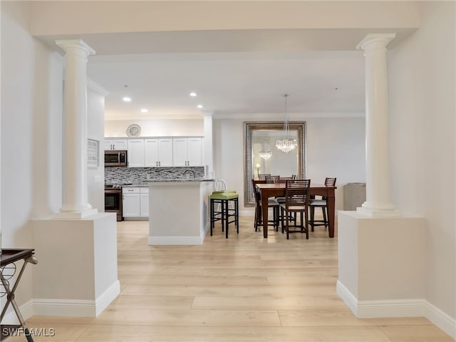 28436 Altessa Way Unit 102, Bonita Springs, FL 34135 - kitchen featuring a breakfast bar area, decorative columns, appliances with stainless steel finishes, ornamental molding, and light wood-style flooring