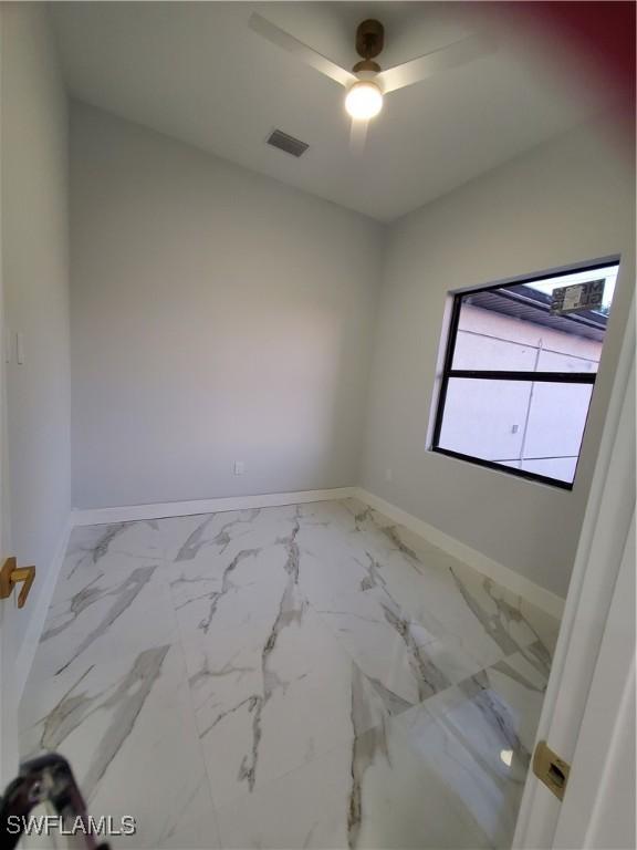 2012 Venice Ave N, Lehigh Acres, FL 33971 - empty room featuring marble finish floor, visible vents, and baseboards