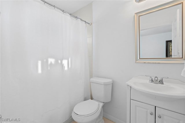 bathroom with toilet, vanity, and baseboards