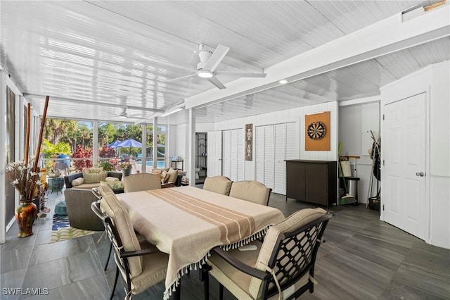dining space with a wall of windows, a ceiling fan, and beamed ceiling