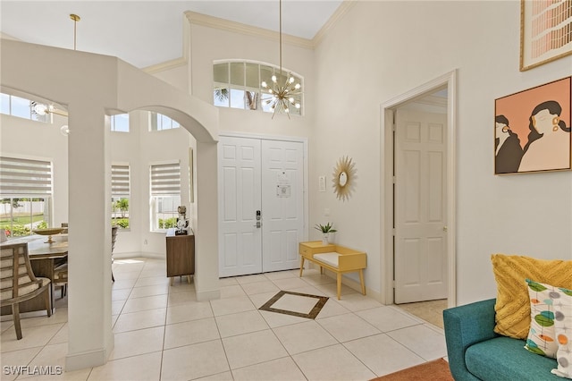 42 Tahiti Rd, Marco Island, FL 34145 - foyer featuring crown molding, light tile patterned floors, an inviting chandelier, a towering ceiling, and baseboards