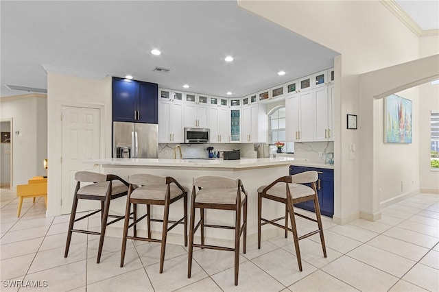 42 Tahiti Rd, Marco Island, FL 34145 - kitchen featuring a breakfast bar area, light tile patterned floors, appliances with stainless steel finishes, light countertops, and ornamental molding