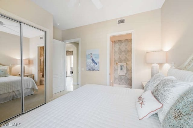carpeted bedroom with ceiling fan, ensuite bath, visible vents, and a closet