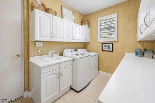 laundry room featuring light tile patterned floors, washing machine and dryer, a sink, baseboards, and cabinet space