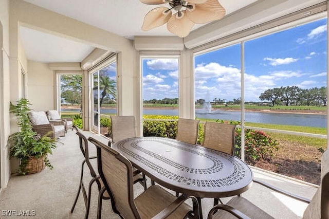 sunroom / solarium with carpet, a water view, a ceiling fan, and outdoor dining space