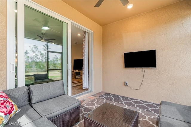 living area with ceiling fan and a textured wall