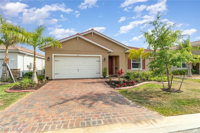 ranch-style house with a front yard, stucco siding, central AC, decorative driveway, and an attached garage