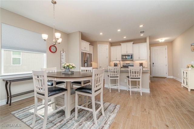 dining area with an inviting chandelier, visible vents, light wood-style flooring, and baseboards