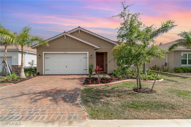 single story home with stucco siding, decorative driveway, a lawn, and an attached garage