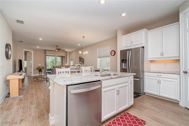 kitchen with a sink, white cabinets, appliances with stainless steel finishes, and light wood-style floors