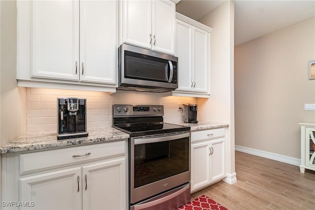 kitchen featuring tasteful backsplash, light wood-style flooring, baseboards, white cabinets, and appliances with stainless steel finishes