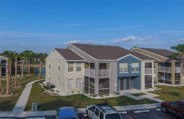142 Santa Clara Dr Unit 7, Naples, FL 34104 - rear view of property with stucco siding, a water view, a balcony, a lawn, and uncovered parking