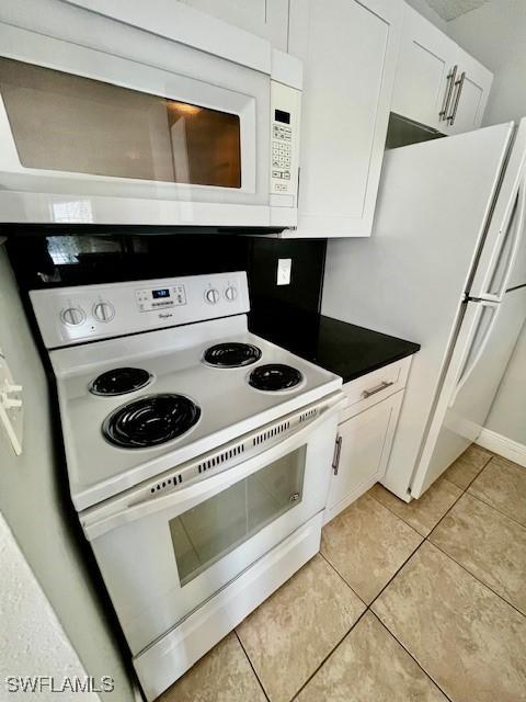 142 Santa Clara Dr Unit 7, Naples, FL 34104 - kitchen featuring dark countertops, white cabinetry, light tile patterned floors, and white appliances